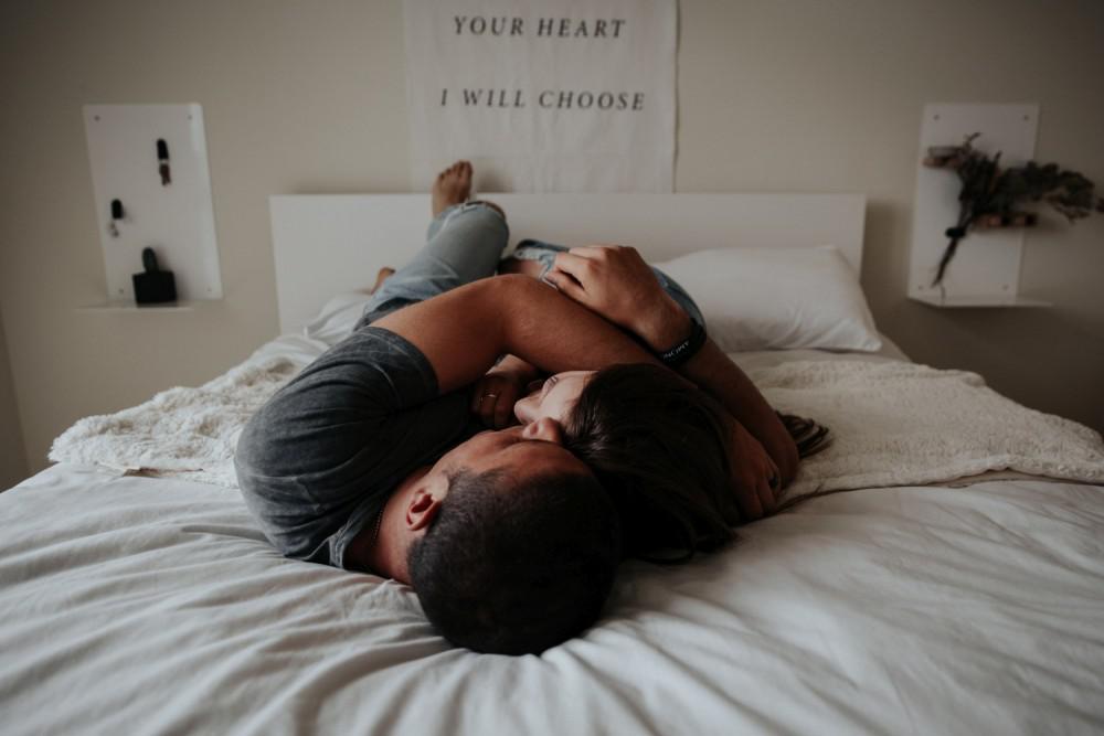man and woman lying on a bed hugging
