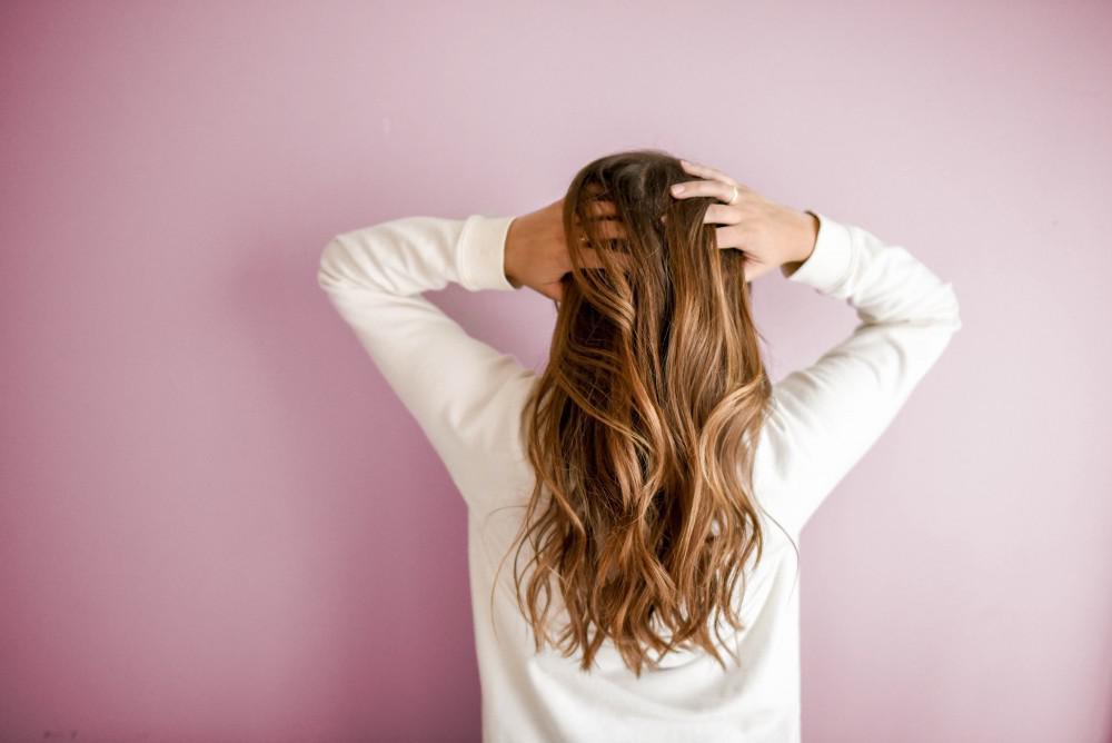a woman's healthy hair resting on the back of her shirt