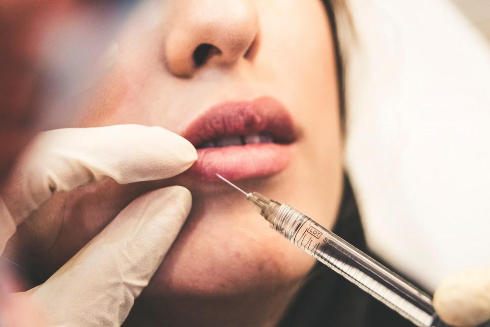 close look at a syringe injecting a woman's lips