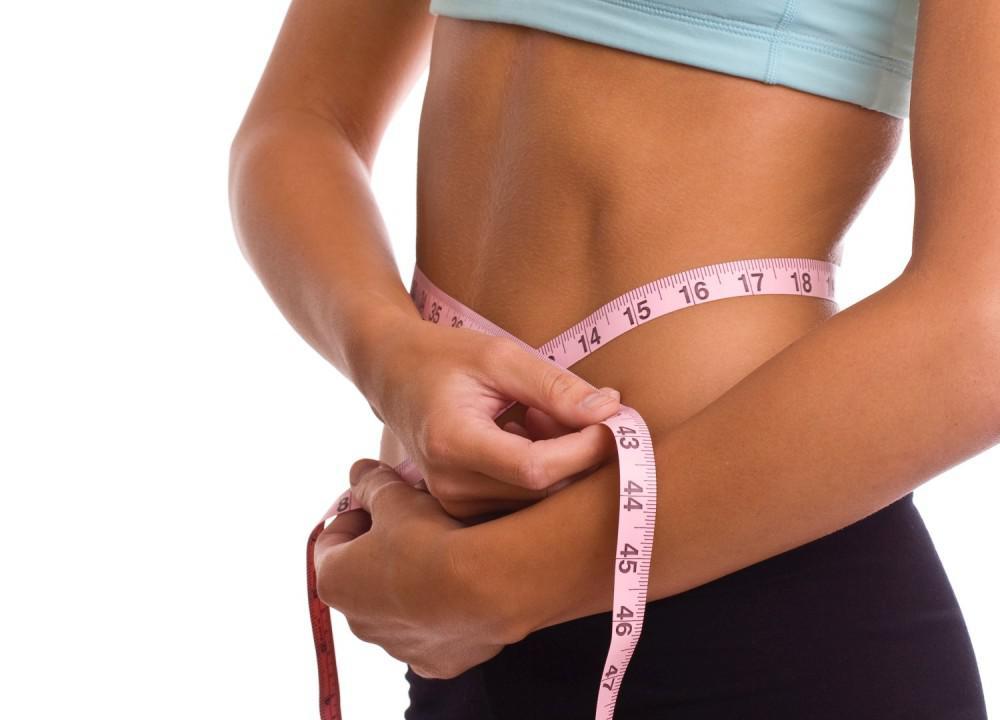 woman holding a measuring tape around her stomach