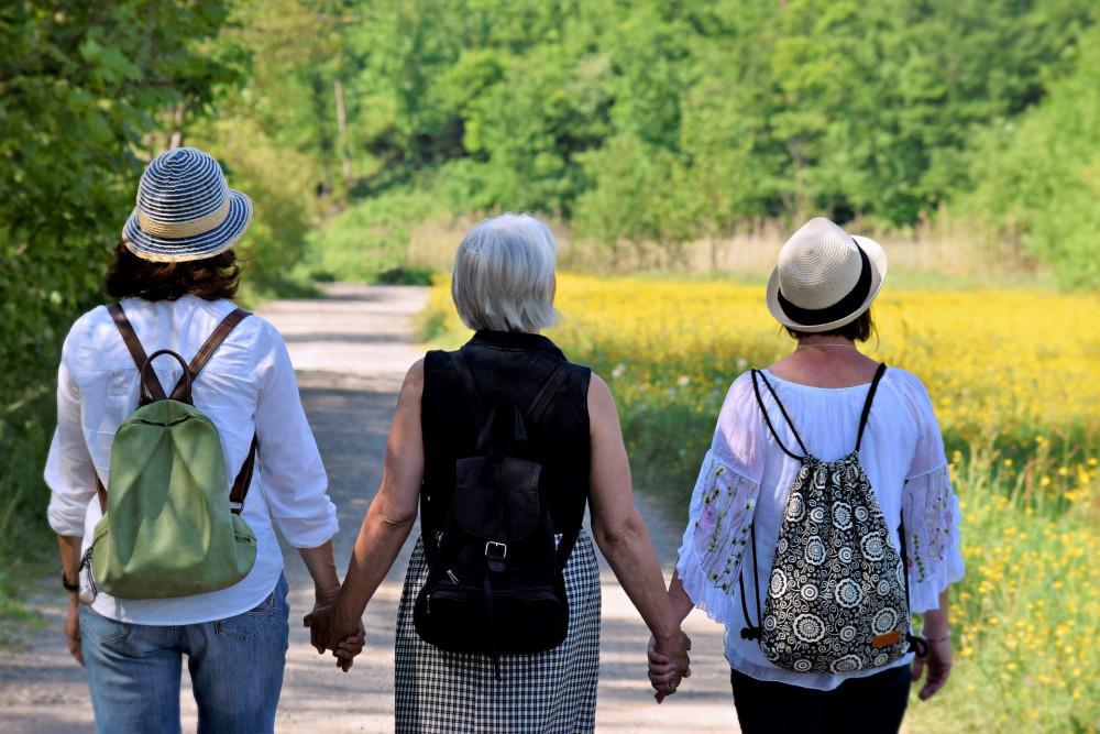 three women walking hand in hand in a park