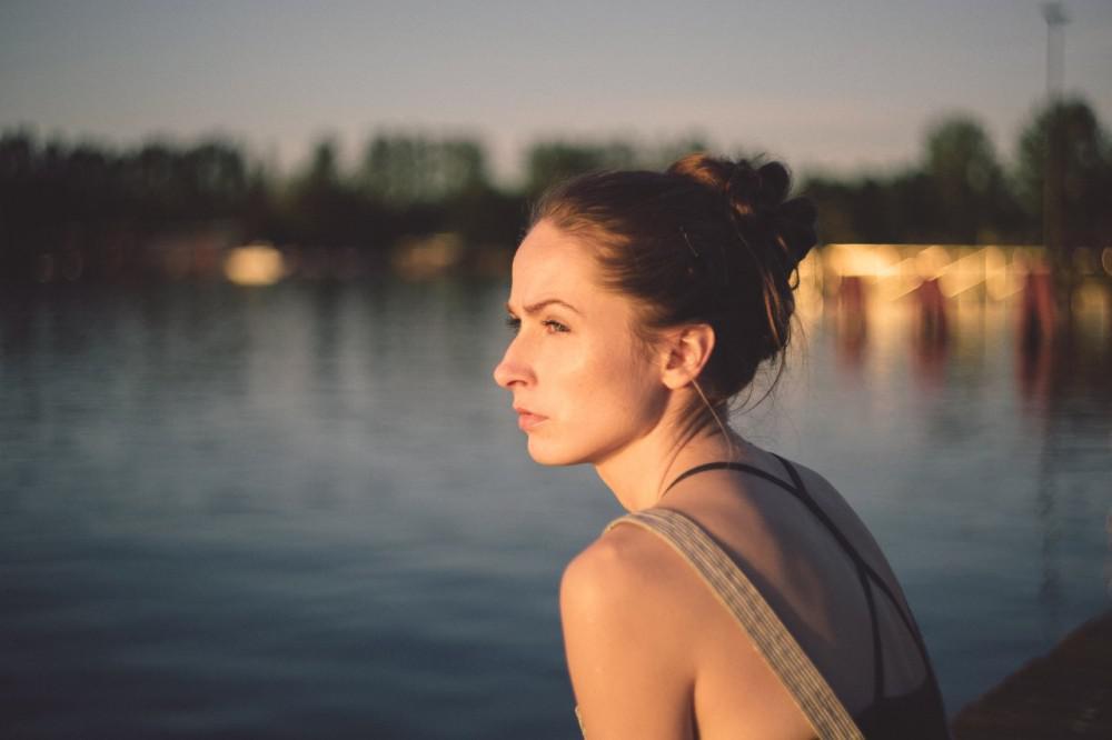 woman near a river looking at the sunset