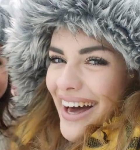 smiling woman with smooth skin wearing a fluffy winter hat