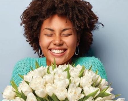 woman with great skin smiling with a bouquet of flowers