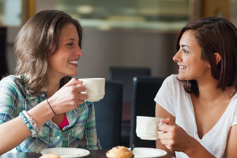 Two smiling women having a cup of coffee at a cafe
