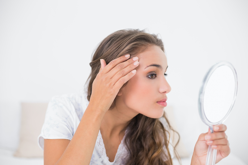 woman examining eyebrows