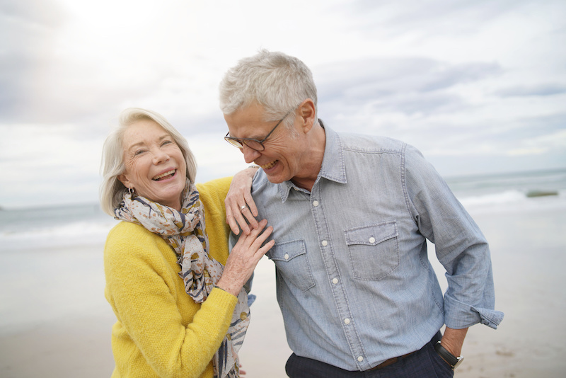 Portrait of happy modern senior couple on beach