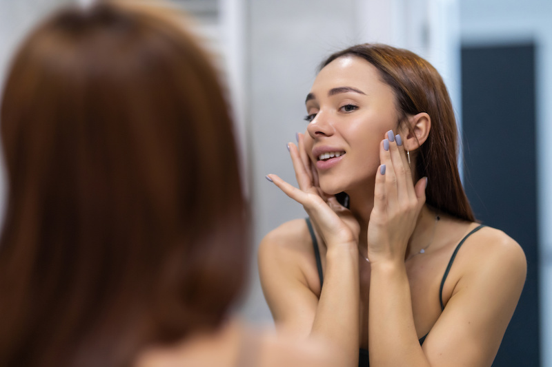 Woman looking in mirror at her skin
